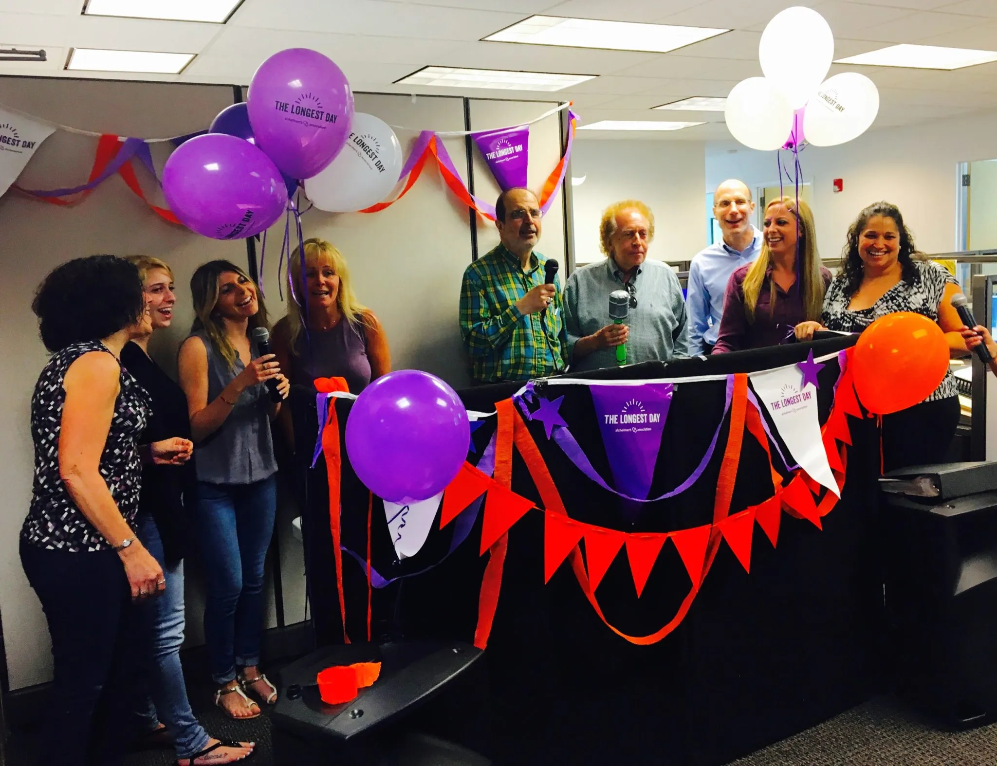 A group singing karaoke together at an event with balloons and streamers