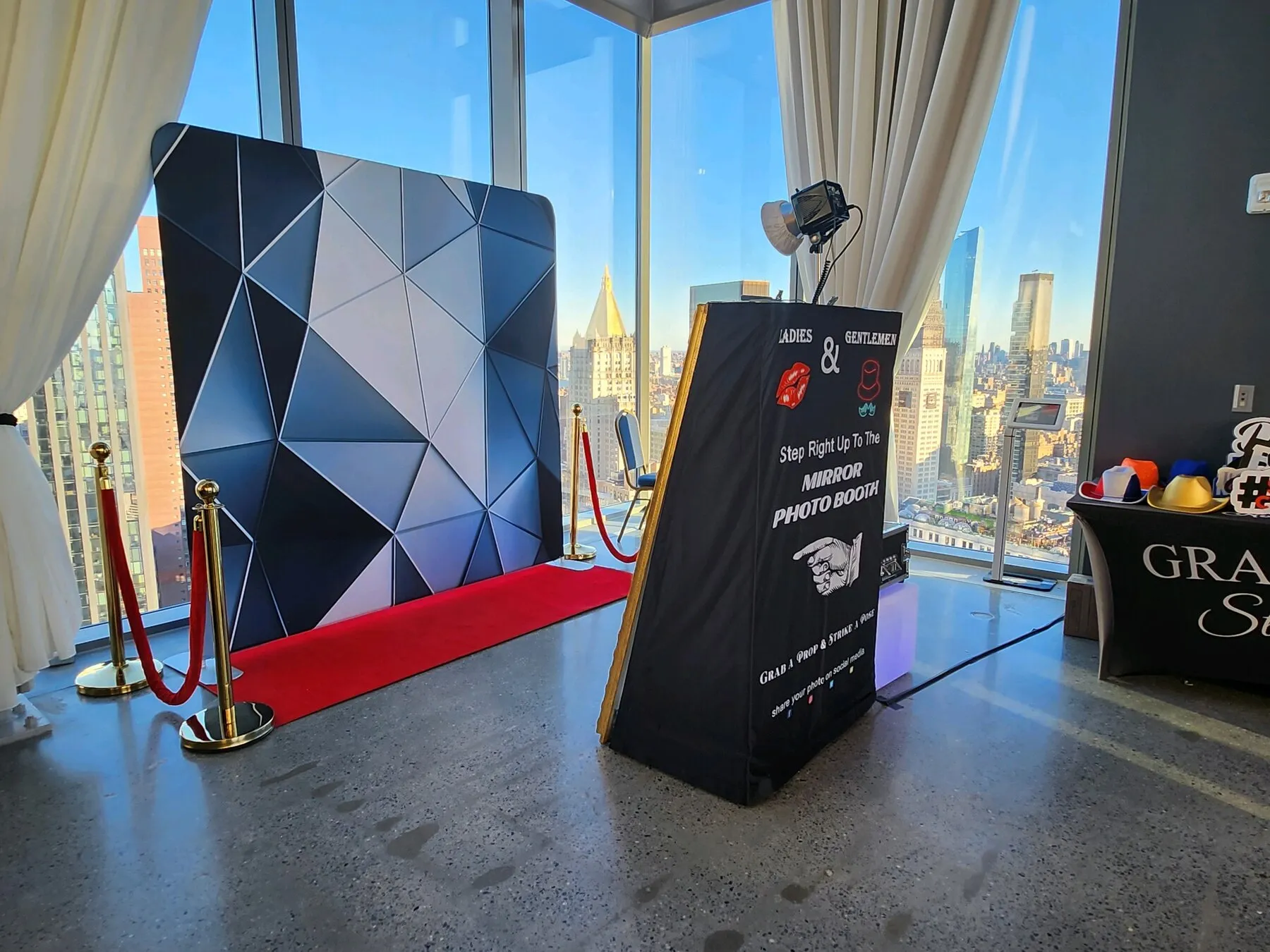 Mirror photo booth with red carpet and NYC skyline backdrop at an event